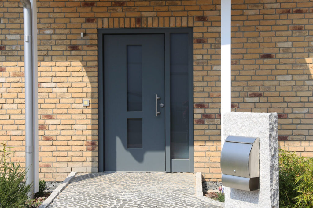 Dark grey door on light brick wall